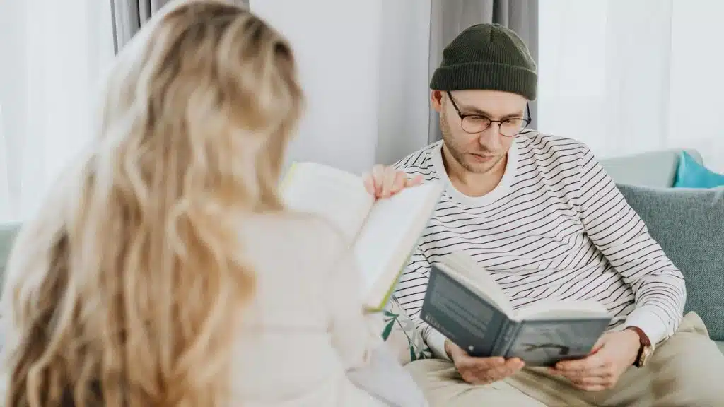 A man and a woman sitting together reading books.