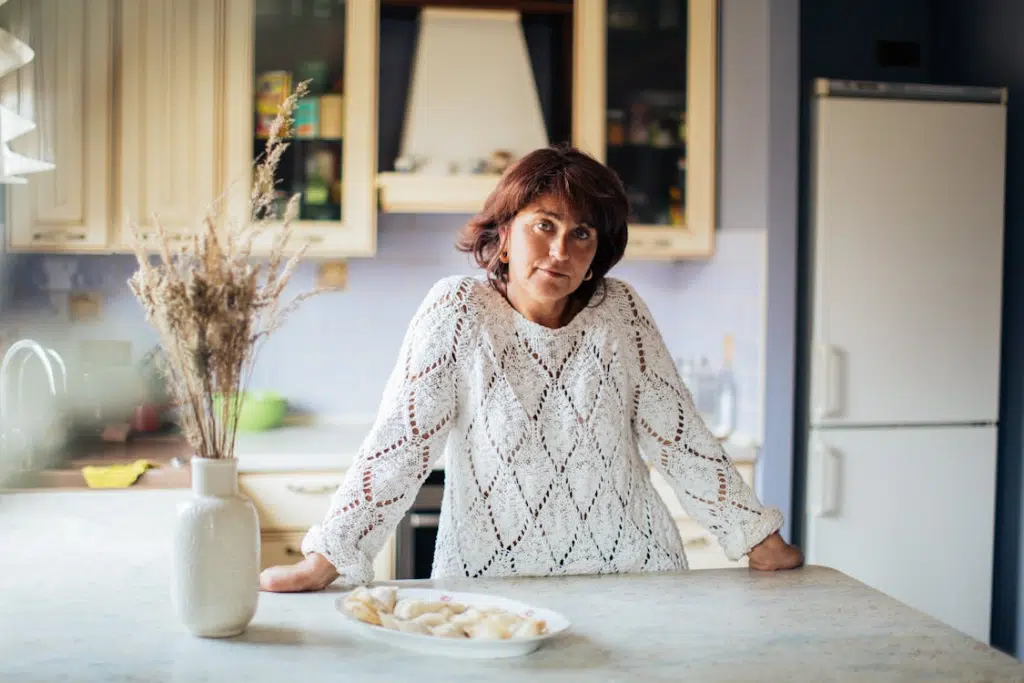 Woman in White Knit Sweater Standing at the Kitchen Counter