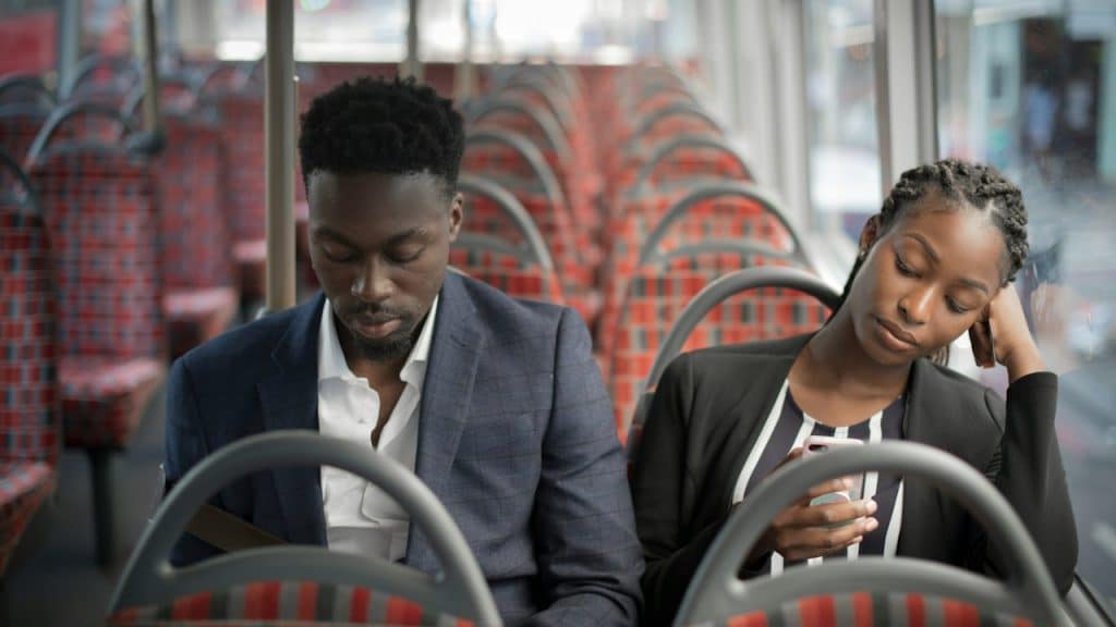 A boring couple using their phones while sitting in the bus.