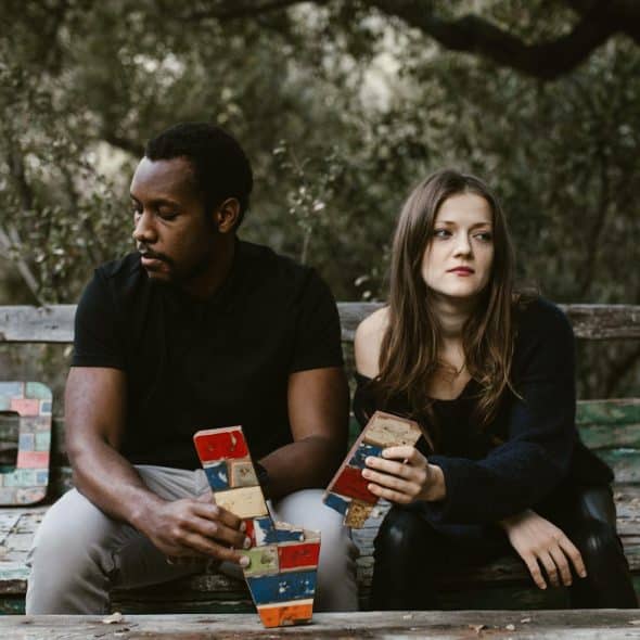 The couple sitting on a bench ignores each other.