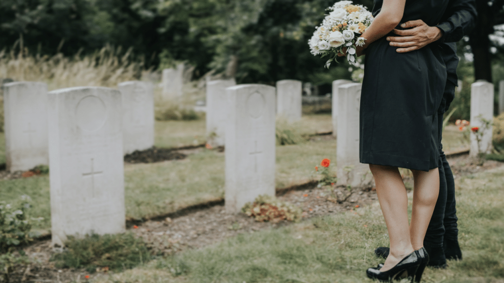 A couple standing by a gravestone