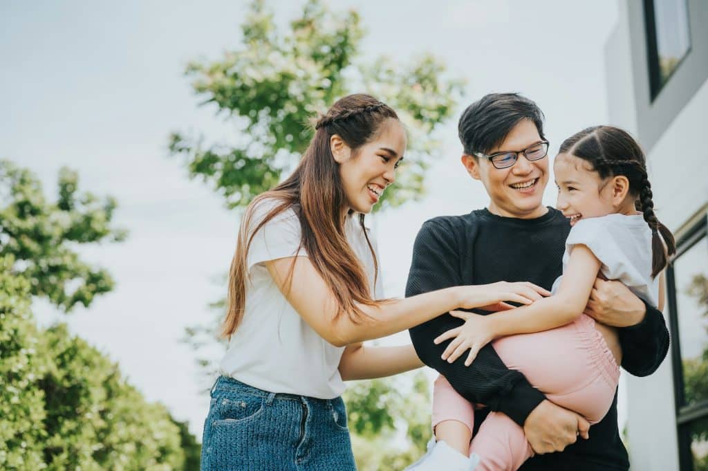 The couple is having fun with their daughter outside their home.