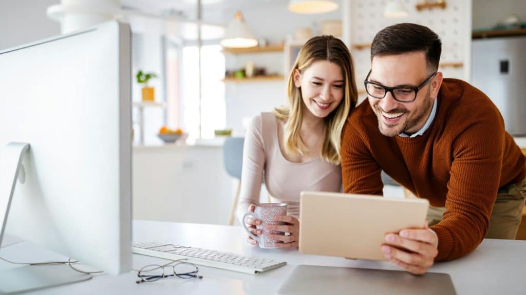Smiling man and woman looking at a tablet together in a bright kitchen.