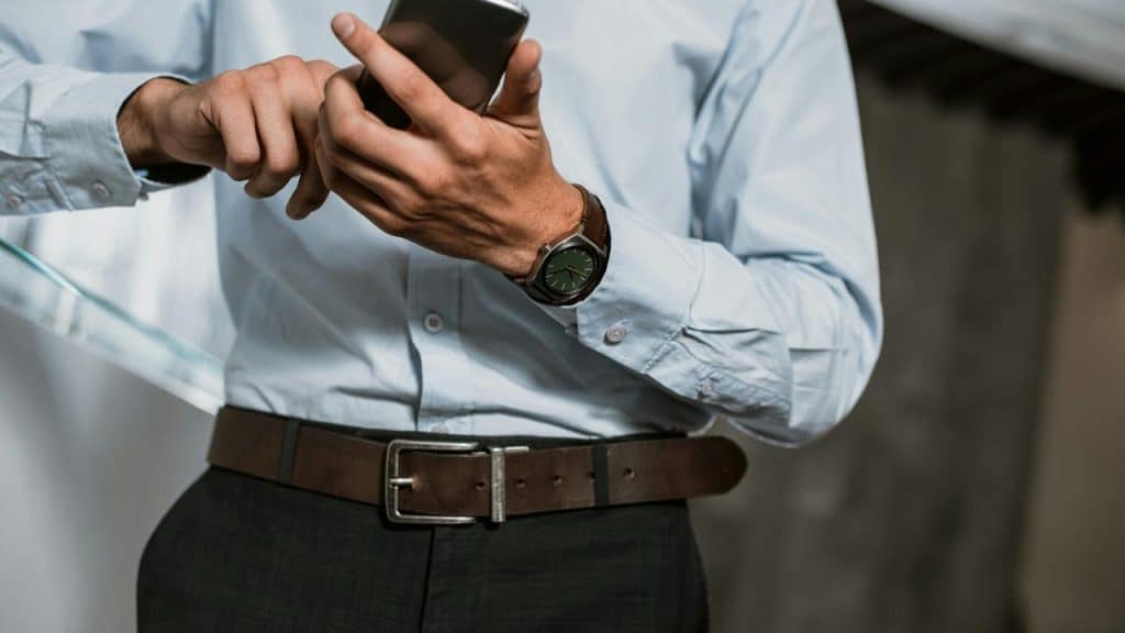 A man in a dress shirt using a smartphone.