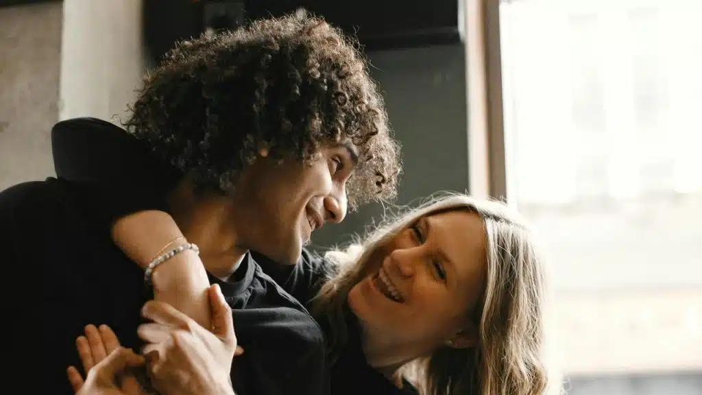 A couple smiling and embracing each other indoors.