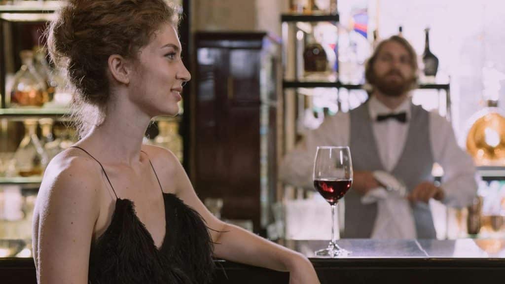 A woman sitting at a bar with a glass of red wine.