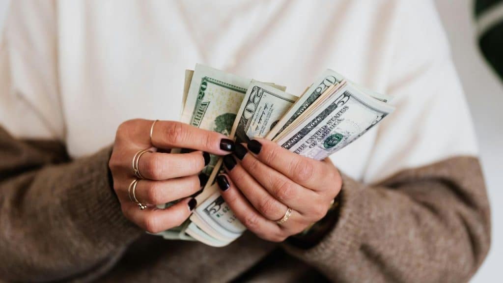 A person counting a stack of US dollar bills.