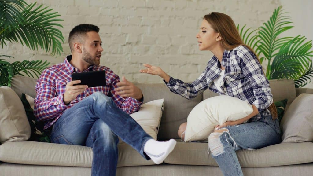 A couple arguing while sitting on a sofa.