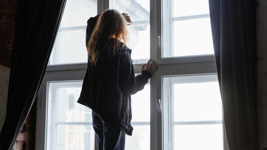 A person standing by a window looking outside.