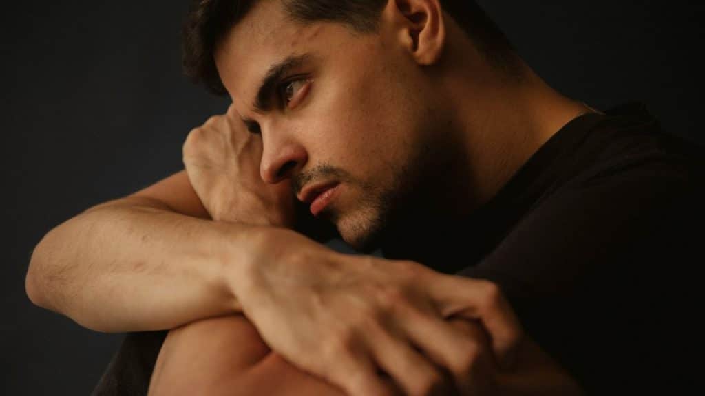 A serious man with his head resting on his arms is looking to the side.
