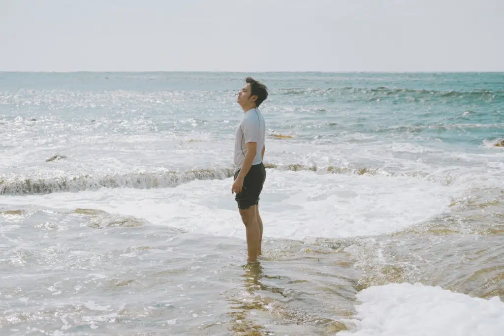 Man Standing in Water on Seashore