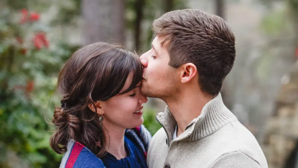 A man kissing his wife’s forehead