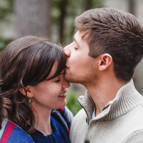 A man kissing his wife’s forehead