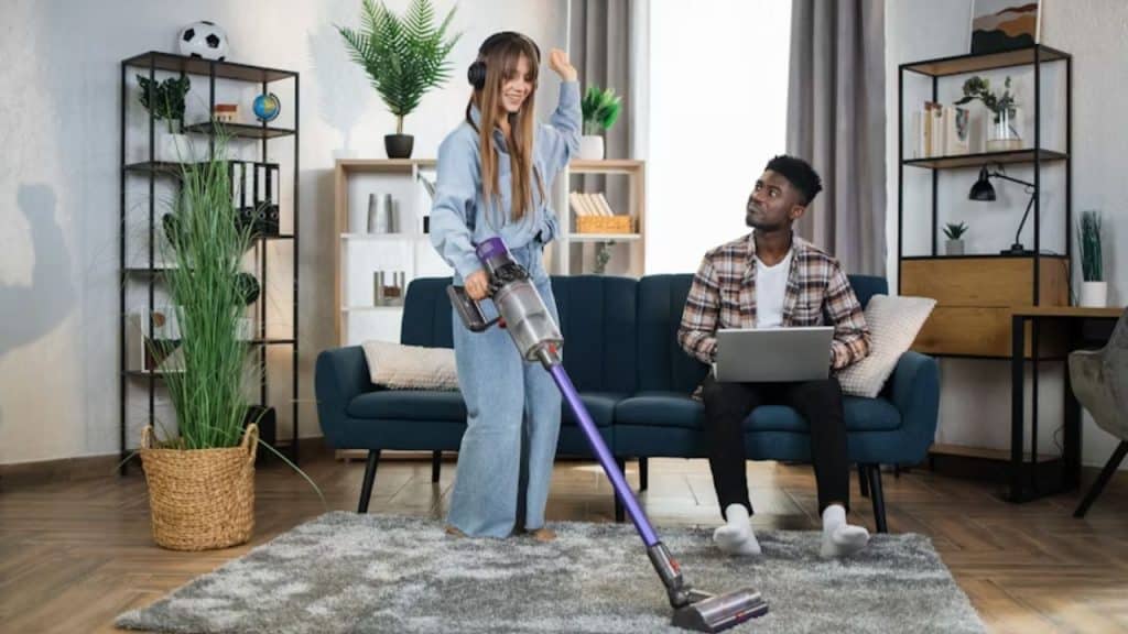 Woman cleaning the house while her partner watches silently