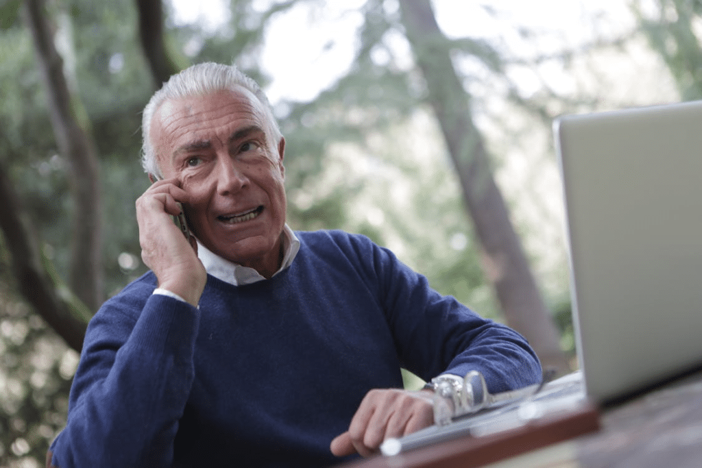 Man in Blue Sweater Sitting Near Wooden Table