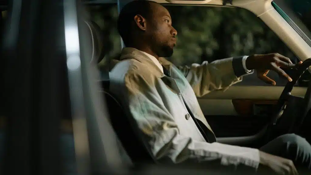A man sitting alone in a car at night.