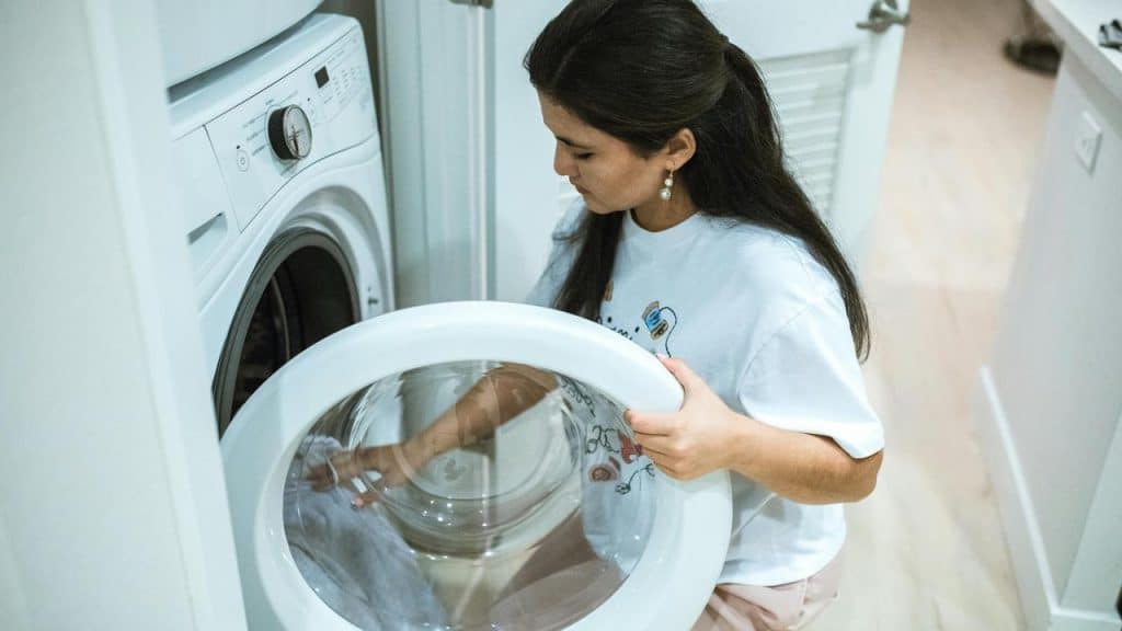 A woman loading clothes into a washing machine.