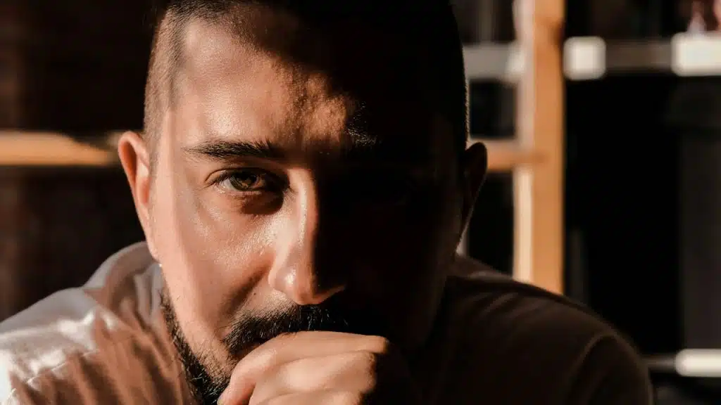 A serious man with shadows covering half his face.