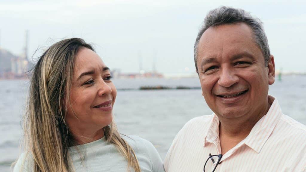 A couple standing on a pier with the ocean in the background.