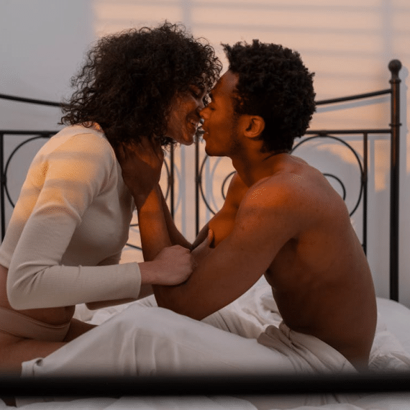 Couple Sitting on Bed and Kissing