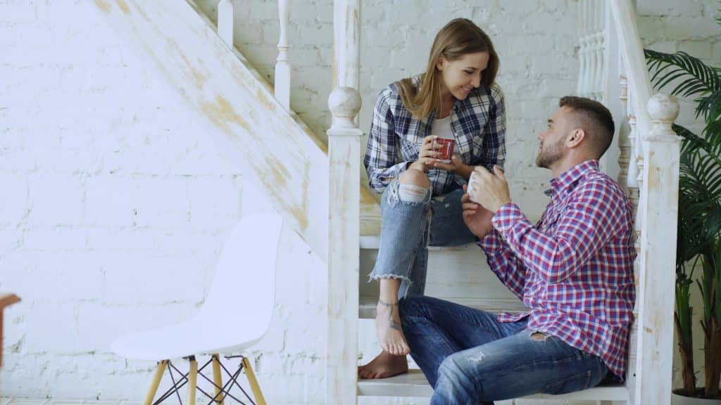 The couple is talking while sitting on the stairs.