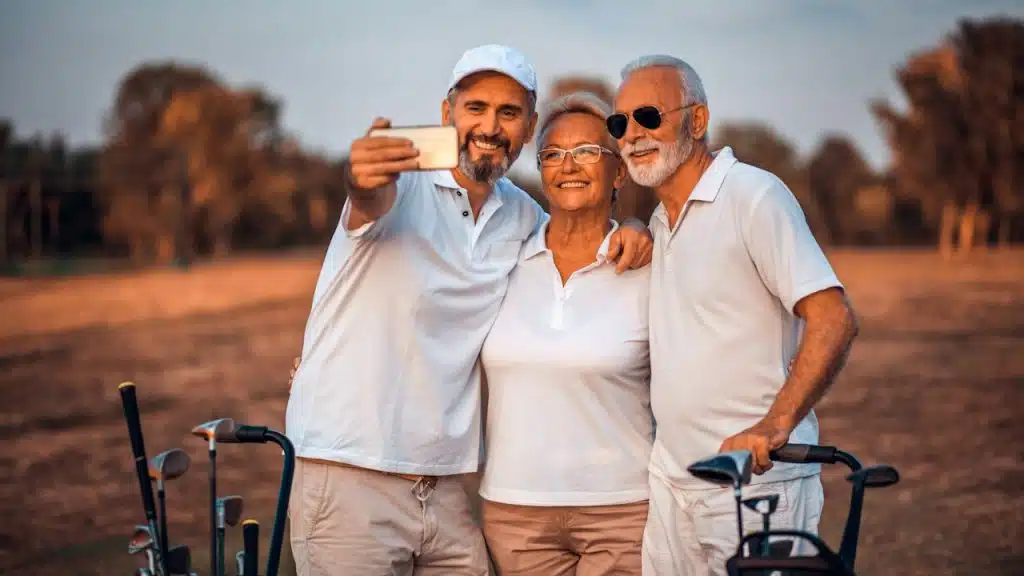 A man taking a selfie with his parents on a golf course.