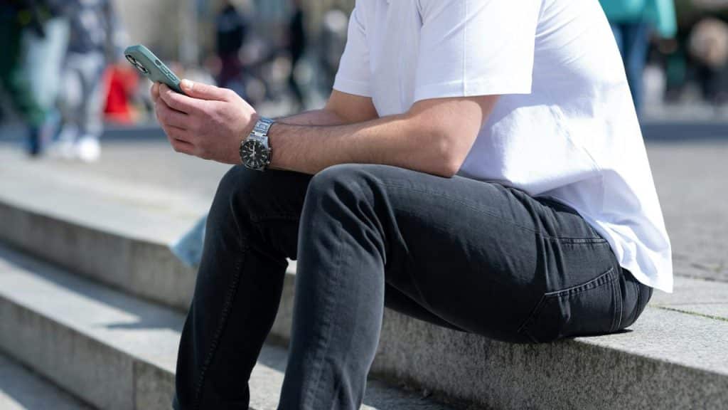 A person sitting on outdoor steps while looking at a smartphone.