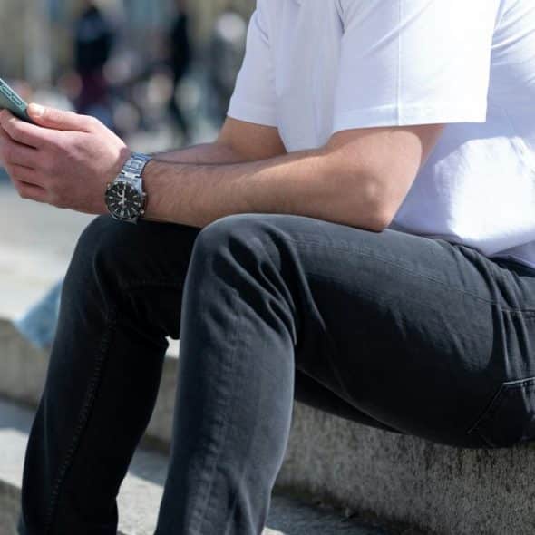 A person sitting on outdoor steps while looking at a smartphone.