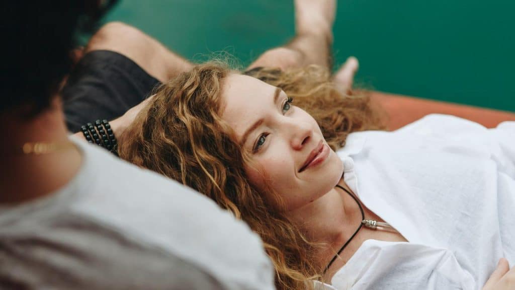 A woman with curly hair lying down and smiling softly.