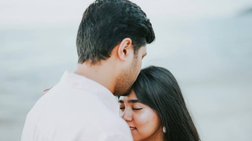 A man kissing his partner’s forehead.