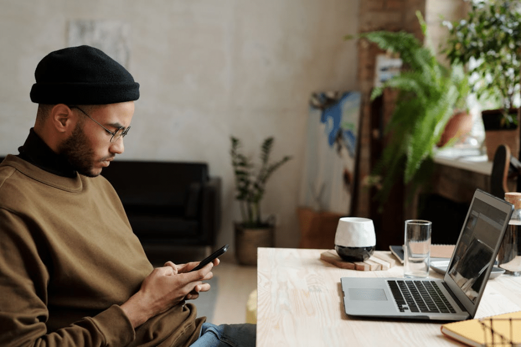 Man in Brown Sweater using Black Smartphone