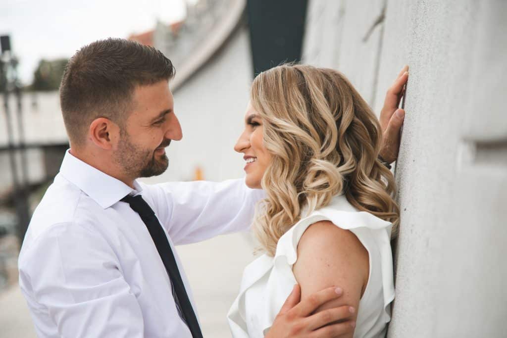 The couple is smiling at each other while spending time outdoors.