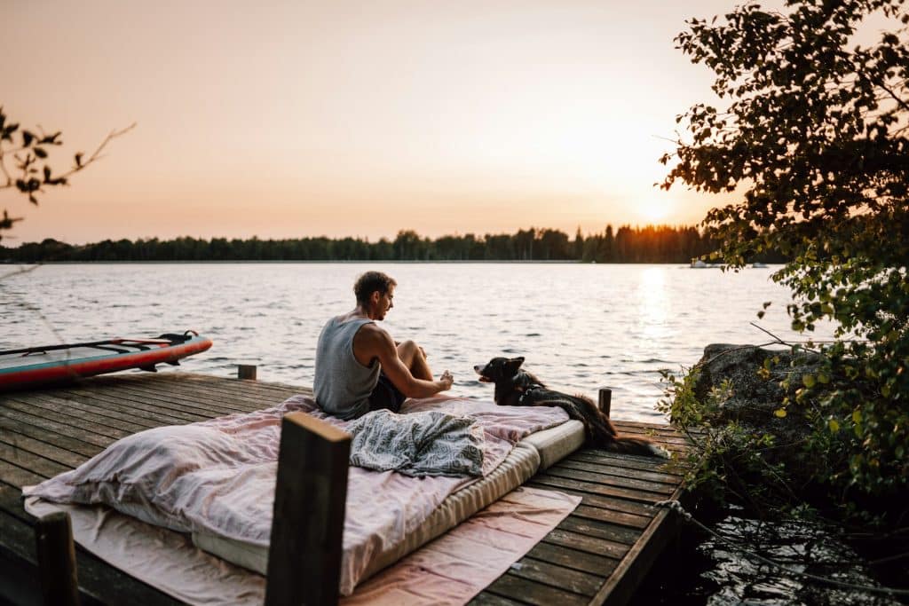 The man is sitting on the dock.