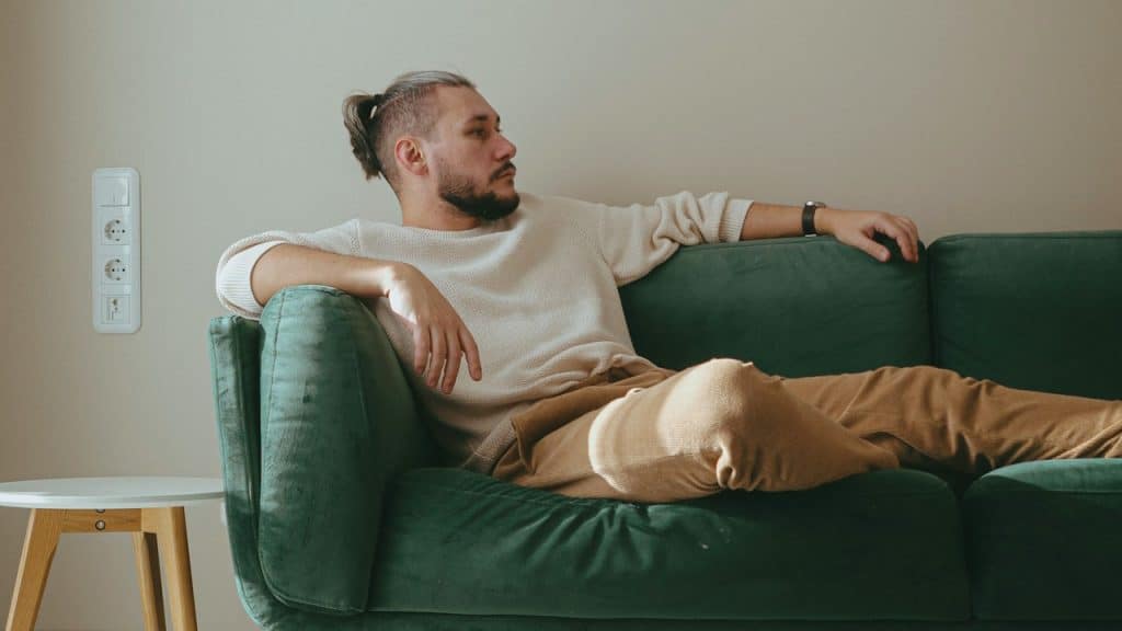 A man with a ponytail chilling on his couch.