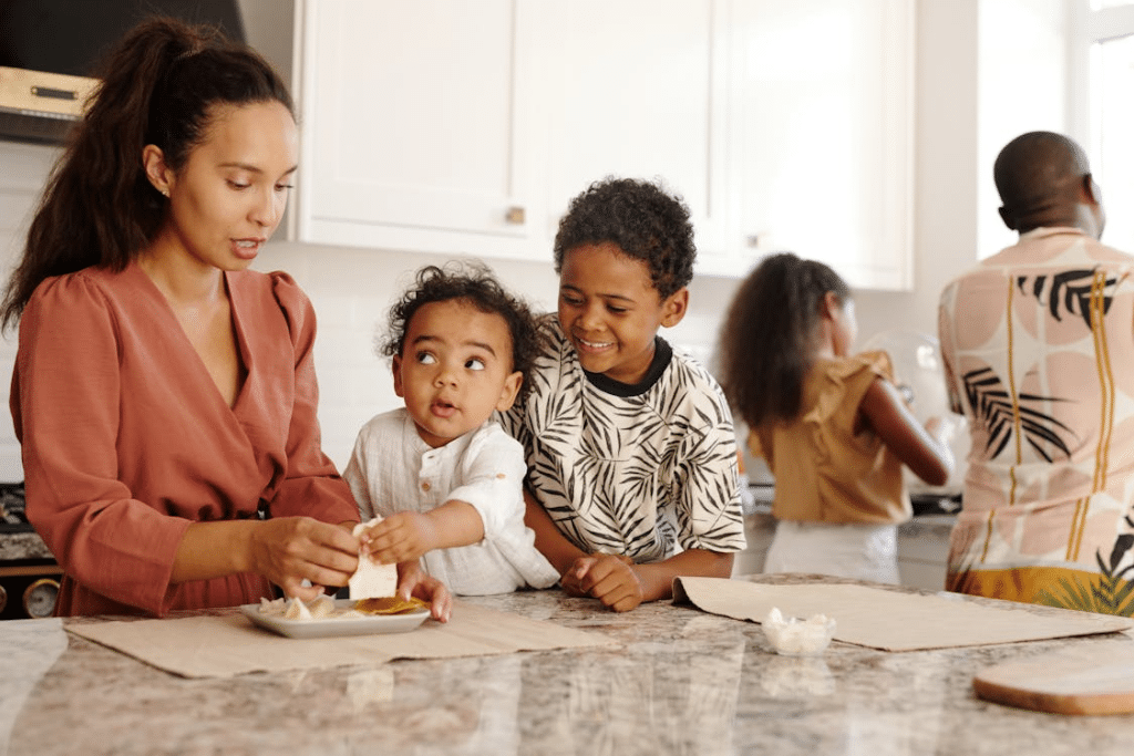 Mother and Smiling Children by Table in Kitchen