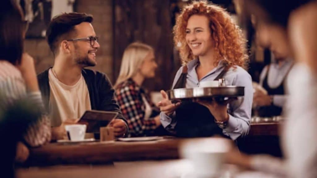 A man smiling and thanking a server at a café.