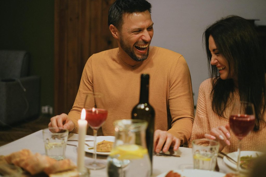 The man and woman are laughing while having dinner.