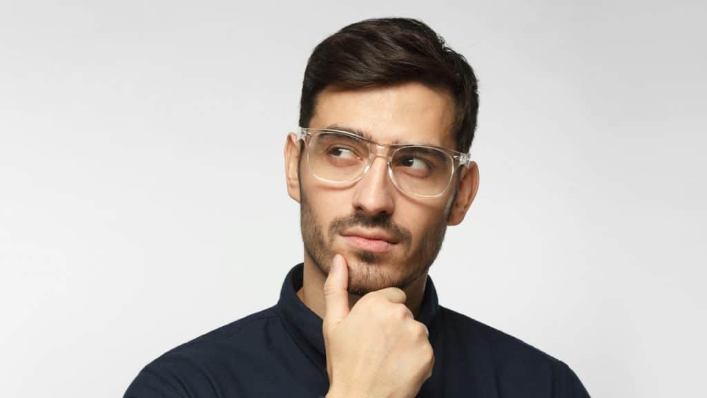 A man wearing glasses and thinking. 