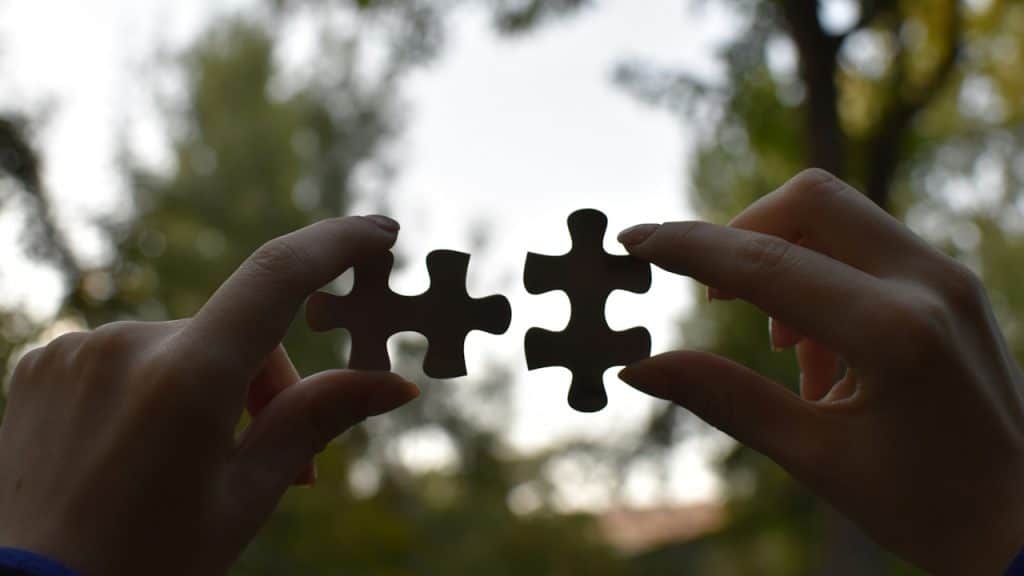 Two hands holding connecting jigsaw pieces.