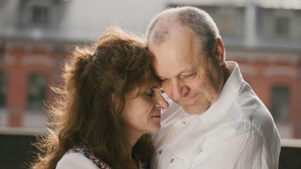 Mature couple embracing with their foreheads touching, eyes closed.