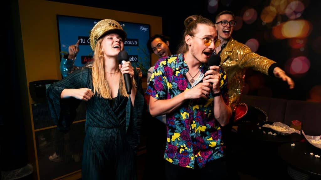 A group of friends singing and laughing together at a karaoke night.