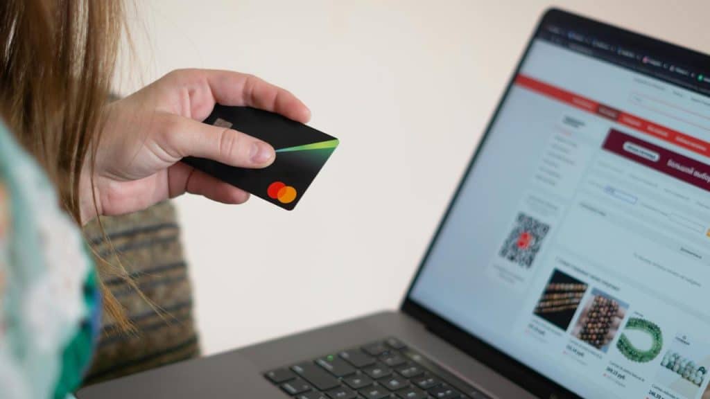 A person holding a credit card while shopping online on a laptop.