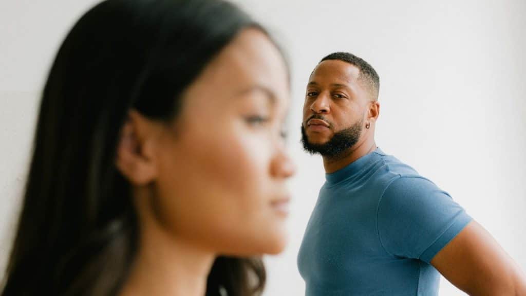 Black man in blue shirt looking over the shoulder of a blurry woman in the foreground.