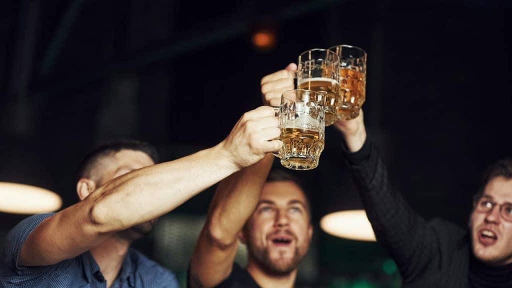 A group of men raising beer mugs in a toast at a bar.