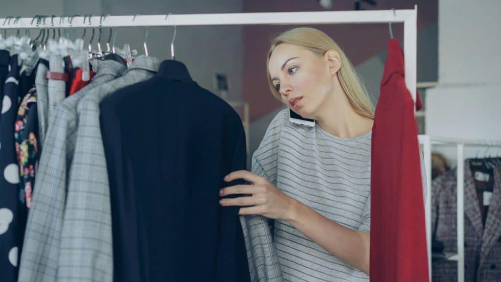 A woman shops for clothes while on the phone