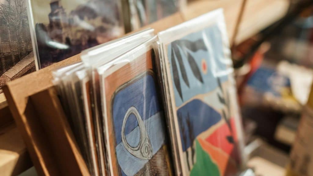 A display of colorful art prints in protective sleeves.