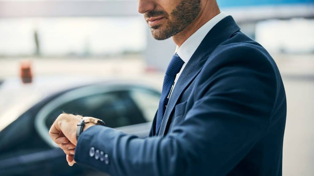 A man in a blue suit looking at his watch.