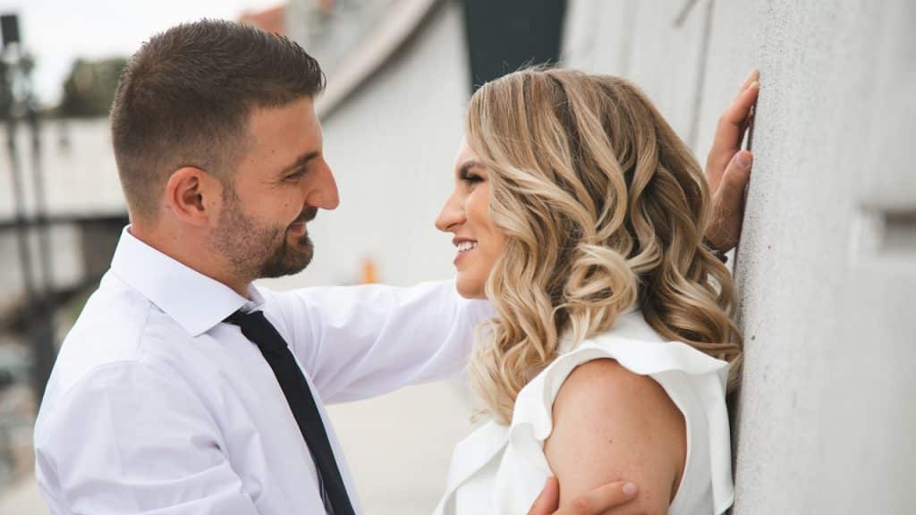 A couple smiling at each other outdoors.