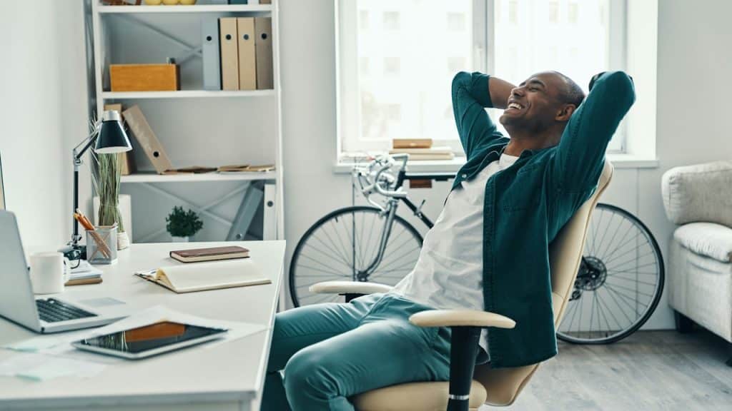 A man stretching in his chair while working from home.