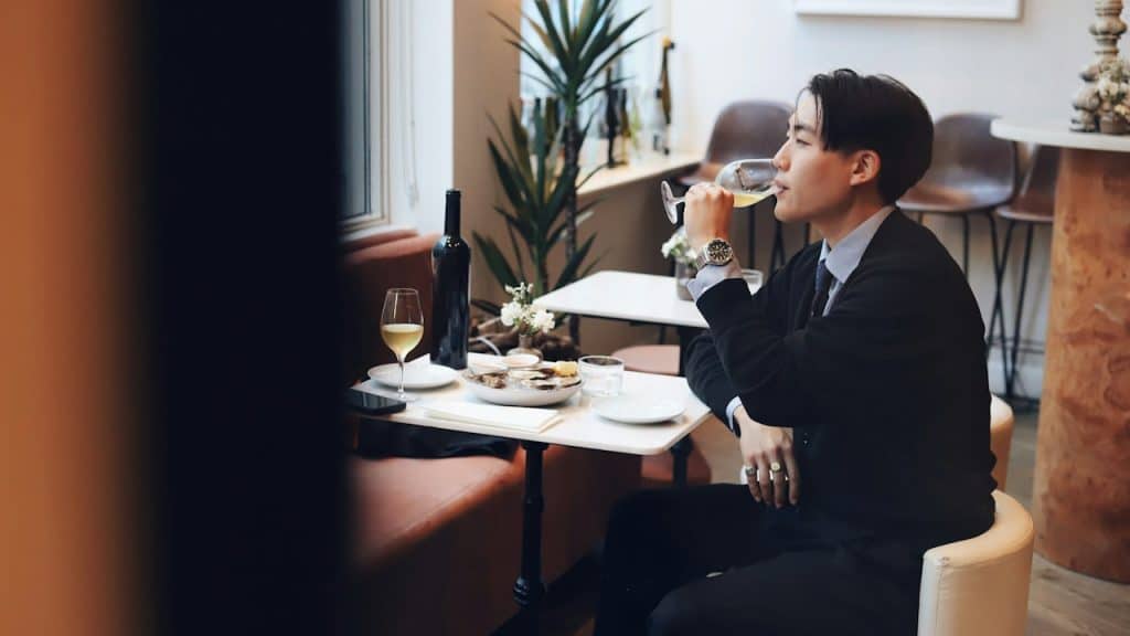 A man alone at a restaurant having a meal and drinking some wine.